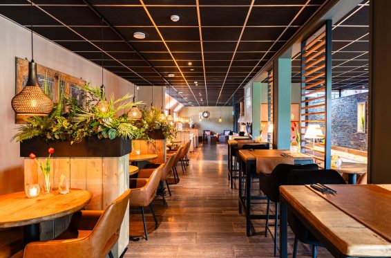 Interieur van het wellnessrestaurant bij sauna Thermen & Beauty LeeuwerikHoeve in Burgum, met warme kleuren en comfortabele zitplekken.
