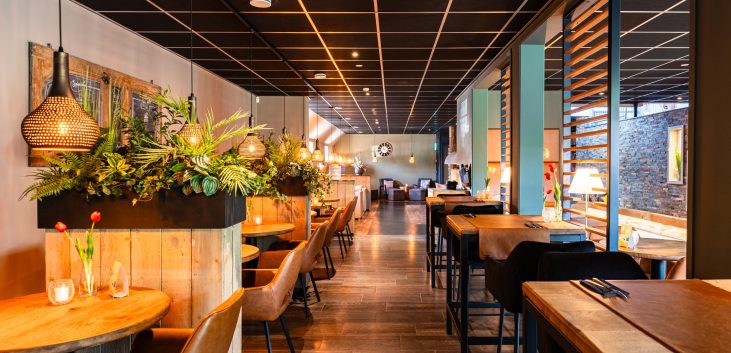 Interieur van het wellnessrestaurant bij sauna Thermen & Beauty LeeuwerikHoeve in Burgum, met warme kleuren en comfortabele zitplekken.